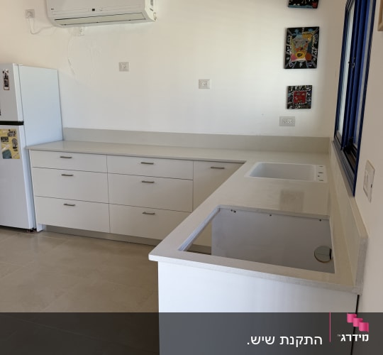 מטבח עם משטחי שיש לבנים וארונות לבנים